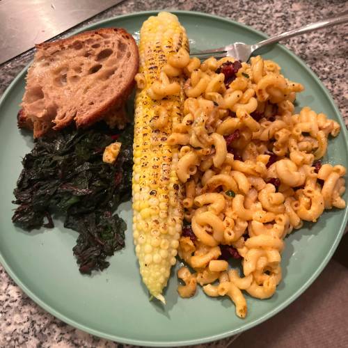 mac and cheese, corn, bread, and wilted greens on a plate
