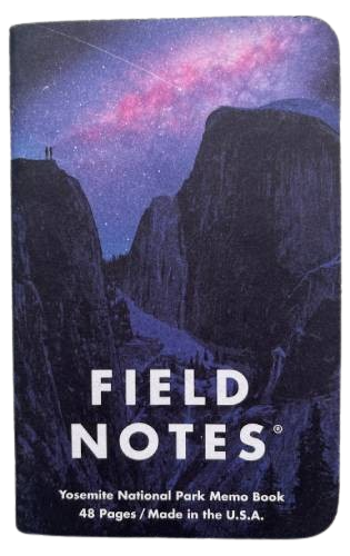 small notebook with a purple cover of yosemite national park. pretty galaxy stuff in the sky.